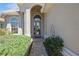 Inviting home entrance featuring an arched doorway, a brick walkway, decorative shrubbery, and a neutral tan color scheme at 512 Weston Pl, Debary, FL 32713