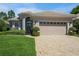 Charming home featuring a lush green lawn, a brick driveway, manicured shrubbery, and a neutral tan color scheme at 512 Weston Pl, Debary, FL 32713