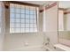 Cozy bathroom featuring a shower-tub combo, complemented by a charming block window and floral accent tiles at 7646 Covedale Dr, Orlando, FL 32818