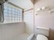 Renovated shower with glass block window and neutral tiles and a toilet at 7646 Covedale Dr, Orlando, FL 32818