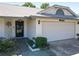 Close-up of the home's facade featuring an attached two-car garage, landscaped garden, and covered entryway at 7646 Covedale Dr, Orlando, FL 32818