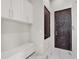 Well-organized mudroom with white cabinetry, bench seating, and a dark wood door at 8521 Lake Nona Shore Dr, Orlando, FL 32827