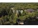 Stunning aerial view showcasing a home with lake access, private dock, and a tennis court nestled among lush trees at 876 Kensington Gardens Ct, Oviedo, FL 32765