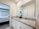 Bathroom with granite sink, white cabinets, and a large mirror reflecting the bedroom at 965 Lido Dr, Howey In The Hills, FL 34737