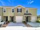 Two-story townhome featuring an attached garage, neutral-tone stucco exterior, and well-manicured landscaping at 965 Lido Dr, Howey In The Hills, FL 34737