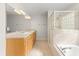 Bathroom featuring a vanity with double sinks, a glass-enclosed shower, and a soaking tub with glass block window at 1019 Spring Landing Dr, Winter Garden, FL 34787