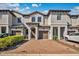 Townhouse exterior with brick paved driveway, brown garage doors, and neutral paint against a blue sky at 1298 Royal St George Blvd, Davenport, FL 33896