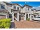 Townhouse exterior showing a brick paved driveway, neutral paint, brown garage doors, and landscaping at 1298 Royal St George Blvd, Davenport, FL 33896