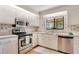 Well-lit kitchen featuring stainless steel appliances, white cabinetry, and a garden window at 1912 Abbington St # Ge, Apopka, FL 32712