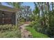 A serene backyard featuring lush landscaping, a stone path, and a charming wooden deck at 1923 Osman Ave, Orlando, FL 32806