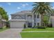 Charming two-story home with a well-manicured lawn, beautiful landscaping, and a large palm tree at 1923 Osman Ave, Orlando, FL 32806
