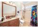 A well-lit bathroom with a granite countertop and a colorful shower curtain at 1984 Windermere Rd, Windermere, FL 34786