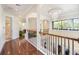 Bright hallway with hardwood floors, chandelier, railing, arches, and lots of natural light at 1984 Windermere Rd, Windermere, FL 34786