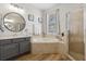 Well-lit bathroom featuring a soaking tub, glass shower, gray vanity, and neutral tile at 2315 Cypress Trace Cir, Orlando, FL 32825