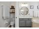 Cozy bathroom features gray vanity, round mirror, floating shelves, and a toilet at 2315 Cypress Trace Cir, Orlando, FL 32825