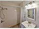 Bright bathroom featuring a tiled shower with pebble flooring, a vanity, and modern lighting fixtures at 2381 Roxbury Rd, Winter Park, FL 32789