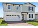 Two-story home with a combination of vertical and horizontal siding, a brick driveway, and an attached garage at 312 Castle Dr, Lake Alfred, FL 33850