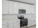Modern white kitchen features stainless appliances, quartz countertops, and ample cabinet space at 312 Castle Dr, Lake Alfred, FL 33850