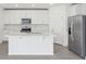 Bright white kitchen features stainless steel appliances and a large kitchen island at 312 Castle Dr, Lake Alfred, FL 33850
