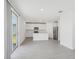 Bright living room with gray tile flooring, sliding glass door, and an open view of the white kitchen at 312 Castle Dr, Lake Alfred, FL 33850