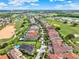 Expansive aerial view of a residential neighborhood adjacent to a scenic golf course and mature trees at 411 Muirfield Loop, Reunion, FL 34747