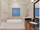 A bright bathroom with a jacuzzi tub, granite countertops, and glass block window at 411 Muirfield Loop, Reunion, FL 34747