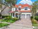 Charming two-story home featuring a red tile roof, arched entryway, two-car garage and beautifully landscaped front yard at 411 Muirfield Loop, Reunion, FL 34747