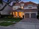 Stunning two-story home with red tile roof, lush landscaping, covered porch, and a two-car garage at 411 Muirfield Loop, Reunion, FL 34747