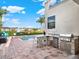 Outdoor kitchen with stainless steel appliances, a grill, a sink, and a table with seating overlooking the pool at 411 Muirfield Loop, Reunion, FL 34747