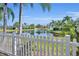 A view from the backyard featuring a white picket fence and a tranquil pond surrounded by palm trees at 4907 Culdesac Ct, St Cloud, FL 34772