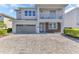 Contemporary two-story home featuring a balcony, gray stucco, a two-car garage, and a brick driveway at 501 Burma St, Kissimmee, FL 34747