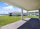 Rear covered patio with brick pavers, offering views of the green backyard and lake at 5074 Sparkling Water Way, Kissimmee, FL 34746