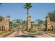 Grand entrance gate with stone pillars, a manicured landscape, and a glimpse of the neighborhood beyond at 631 Reserve Dr, Davenport, FL 33896