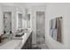 Bright bathroom with double vanity, marble floors, gray cabinets, large mirror and a glass-enclosed shower at 7841 Georgeann St, Winter Park, FL 32792