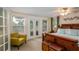 Bright bedroom with French doors to a balcony, a decorative ceiling fan and a seating area with a yellow chair at 809 Poinsettia Dr, Eustis, FL 32726