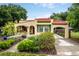 Charming home featuring a red tile roof, arched entry, and a lush, landscaped front yard at 809 Poinsettia Dr, Eustis, FL 32726