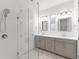 Bright bathroom featuring a glass shower, gray vanity with double sinks, and hexagon-patterned tile flooring at 13087 Salk Way, Orlando, FL 32827