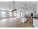 Open-concept living space with wood-look floors, kitchen island, pendant lighting, and natural light from multiple windows at 13087 Salk Way, Orlando, FL 32827