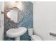 Stylish powder room with blue herringbone tile accent wall and a decorative mirror at 13087 Salk Way, Orlando, FL 32827
