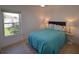 Bedroom featuring a bright blue quilt, bedside tables and a window with view to backyard at 14901 Wild Wood Lily Ct, Orlando, FL 32824