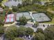 Overhead view of well-maintained tennis courts, parking area, and surrounding natural landscape at 1686 Victoria Gardens Dr, Deland, FL 32724
