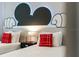 Whimsical bedroom featuring twin beds with red accent pillows, highlighted by a Mickey Mouse themed wall design at 17522 Hidden Forest Dr, Clermont, FL 34714