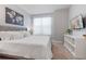 Bright bedroom with a large window, mounted TV, and stylish decor, complemented by a modern display shelf at 17522 Hidden Forest Dr, Clermont, FL 34714