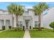 Modern two-story home featuring a well-manicured lawn, stone accents, and decorative palm trees on a sunny day at 17522 Hidden Forest Dr, Clermont, FL 34714