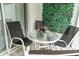 Close up of patio table and chairs with a green plant wall at 17522 Hidden Forest Dr, Clermont, FL 34714
