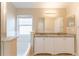 Bright bathroom featuring a double vanity with granite countertop and a large soaking tub at 2104 Remington Pointe Blvd, Kissimmee, FL 34743