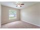 Cozy bedroom featuring neutral carpeting, a window overlooking the backyard, and a ceiling fan at 2104 Remington Pointe Blvd, Kissimmee, FL 34743
