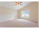 Spacious carpeted bedroom featuring ceiling fan and window with a view of the outdoors at 2104 Remington Pointe Blvd, Kissimmee, FL 34743