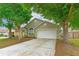 Inviting home exterior showcasing a lush front yard, mature trees, and convenient two-car garage at 2104 Remington Pointe Blvd, Kissimmee, FL 34743