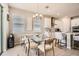 Open dining area with a modern glass table, white cabinets, and stainless steel appliances at 2277 Crossbow St, Clermont, FL 34715